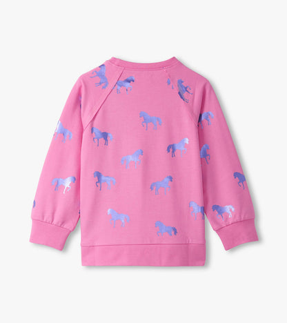 Pink sweater featuring a pattern of blue shimmer horses, with long sleeves and a crew neckline.
