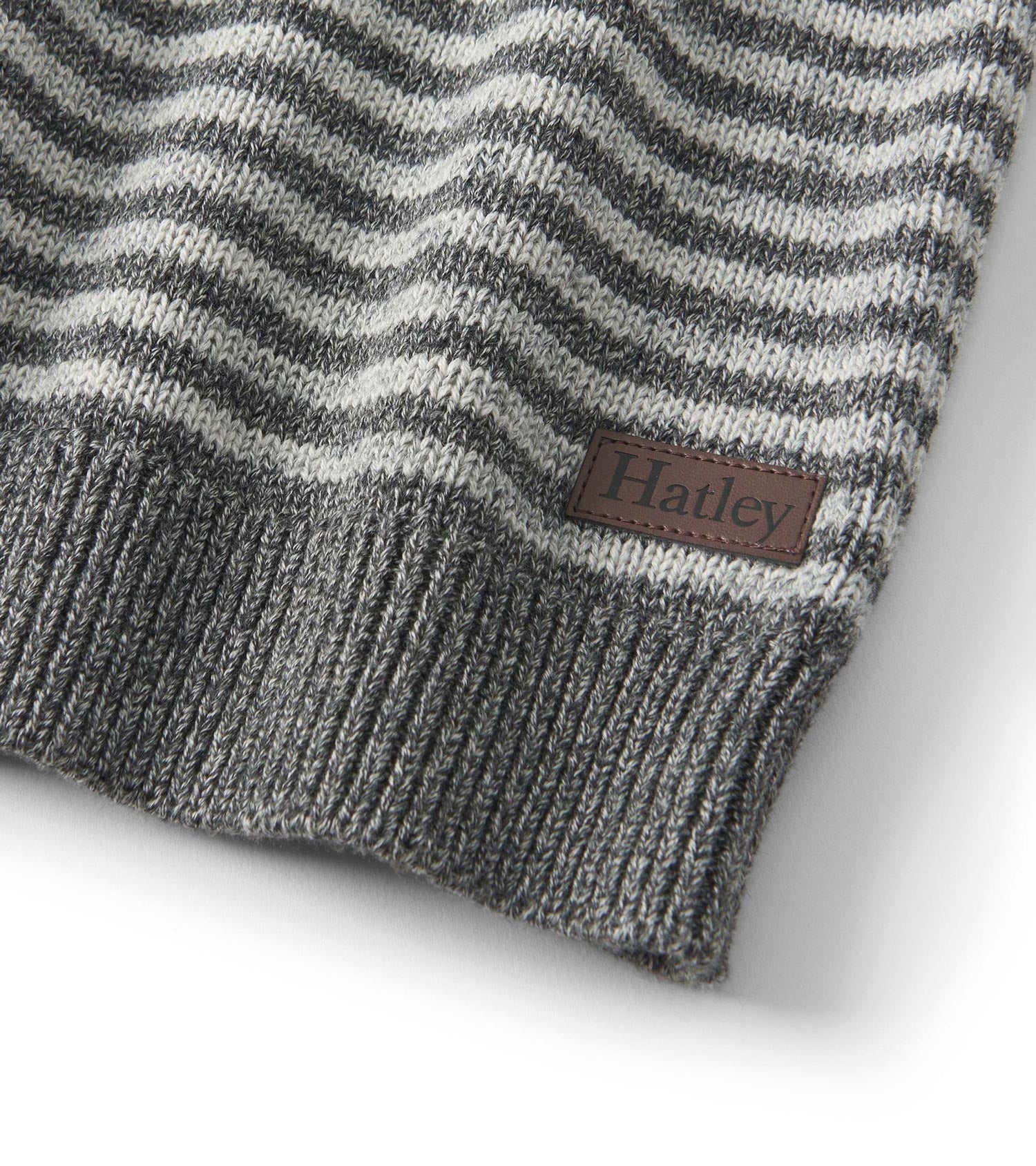 Gray crew neck sweater featuring a speckled stripe pattern and ribbed hem. Includes a small logo patch.