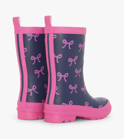 Navy rain boots with pink bow pattern and trim, featuring a sturdy sole and pull tabs for easy wear.