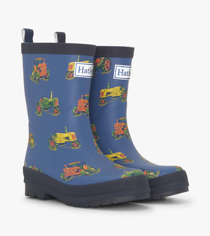 Matte blue rain boots featuring colorful tractor patterns, designed for boys, with pull tabs for easy wear.