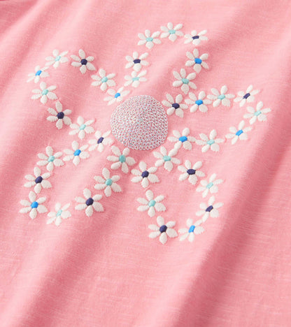 Pink graphic tee featuring embroidered flowers in white, blue, and navy, with puff sleeves for a playful look.