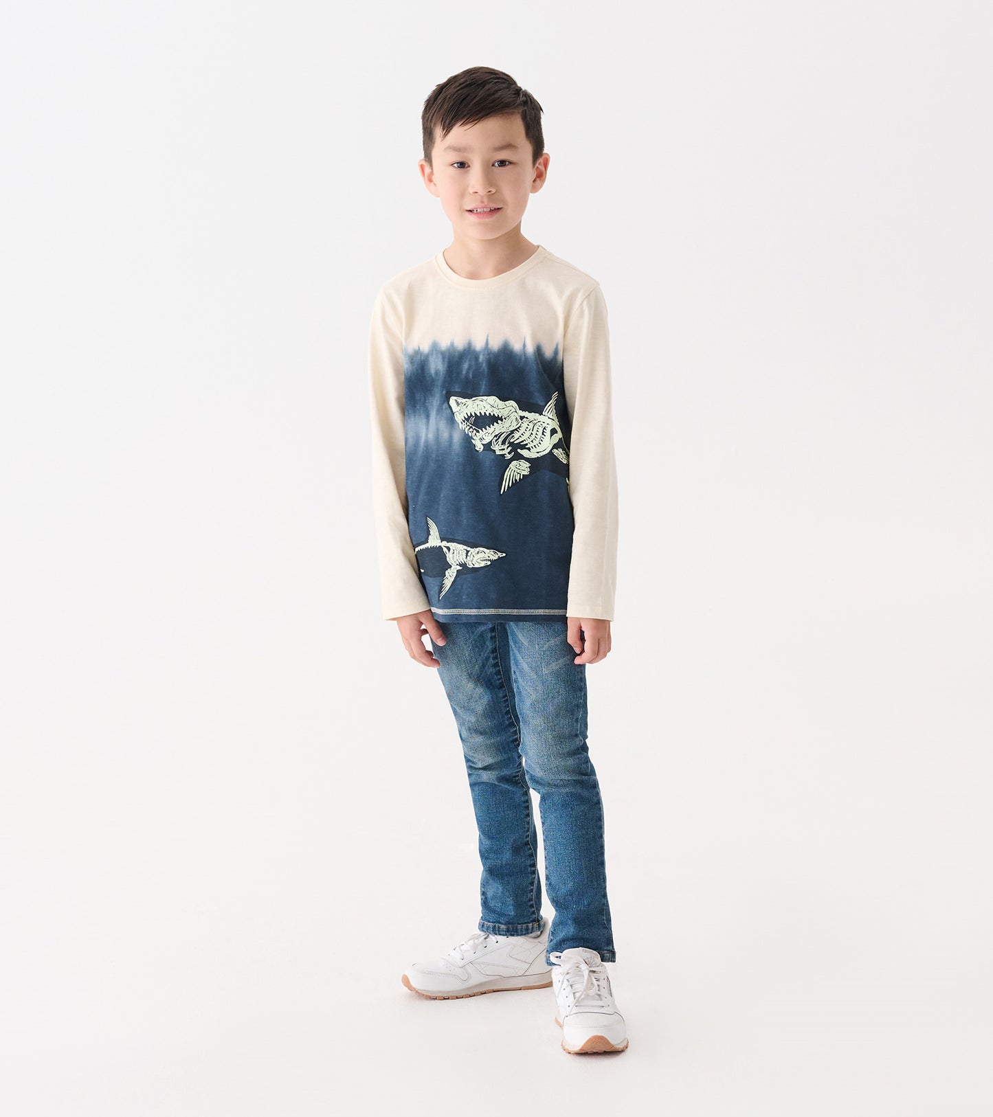 Long sleeve beige graphic tee featuring shark bone prints, with a blue gradient pattern, worn by a boy with jeans.