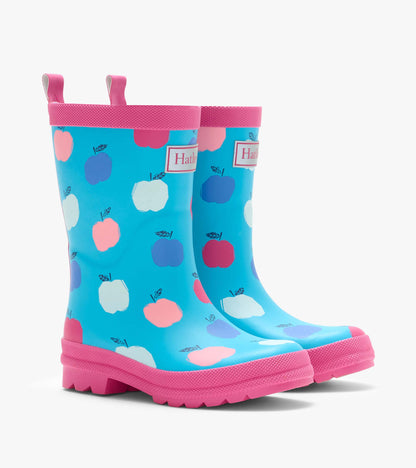 Pair of kids rain boots in blue with pink trim and pink, white, and blue apple print, front angle