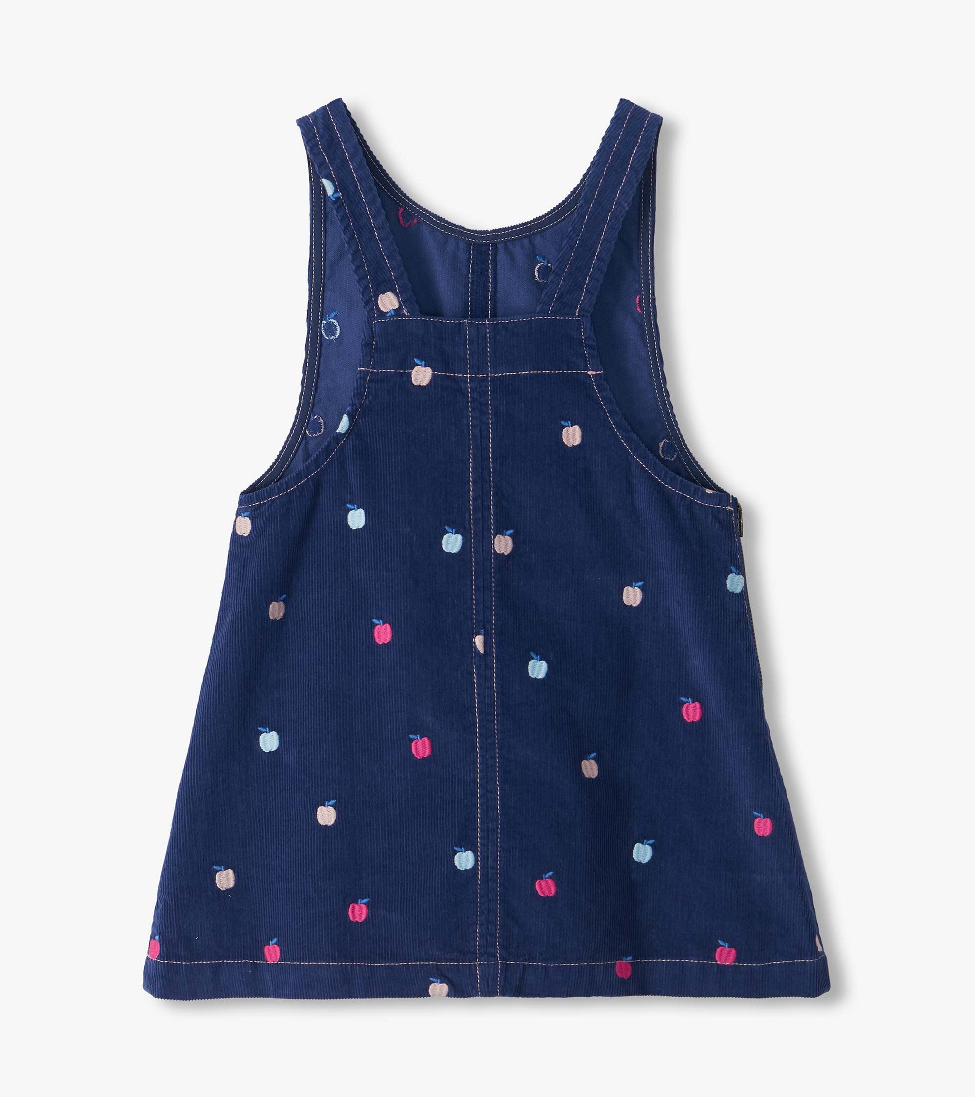 Back view of navy pinafore dress with cross-back straps and scattered embroidered apple pattern