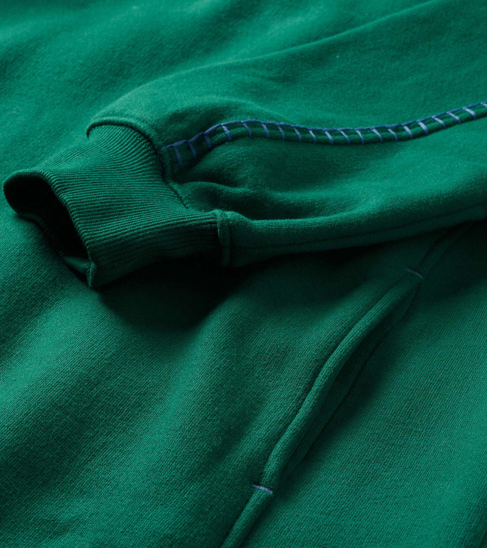 Close-up of the aventurine green dress showing ribbed cuff, pocket seam, and contrast stitching