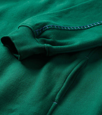Close-up of the aventurine green dress showing ribbed cuff, pocket seam, and contrast stitching