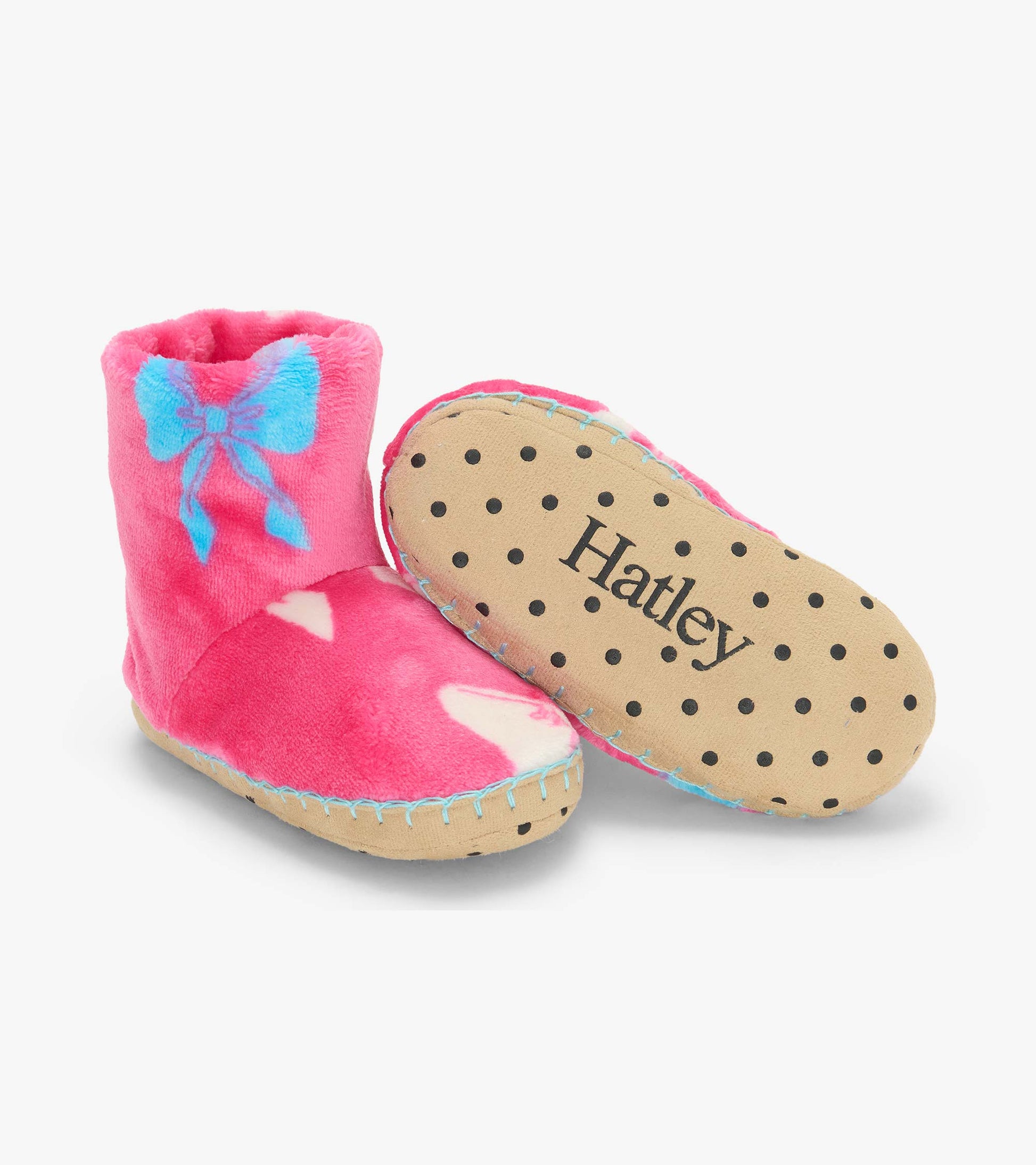 Pink fleece bootie slippers with blue bow print, showing the tan sole with black dots and Hatley logo