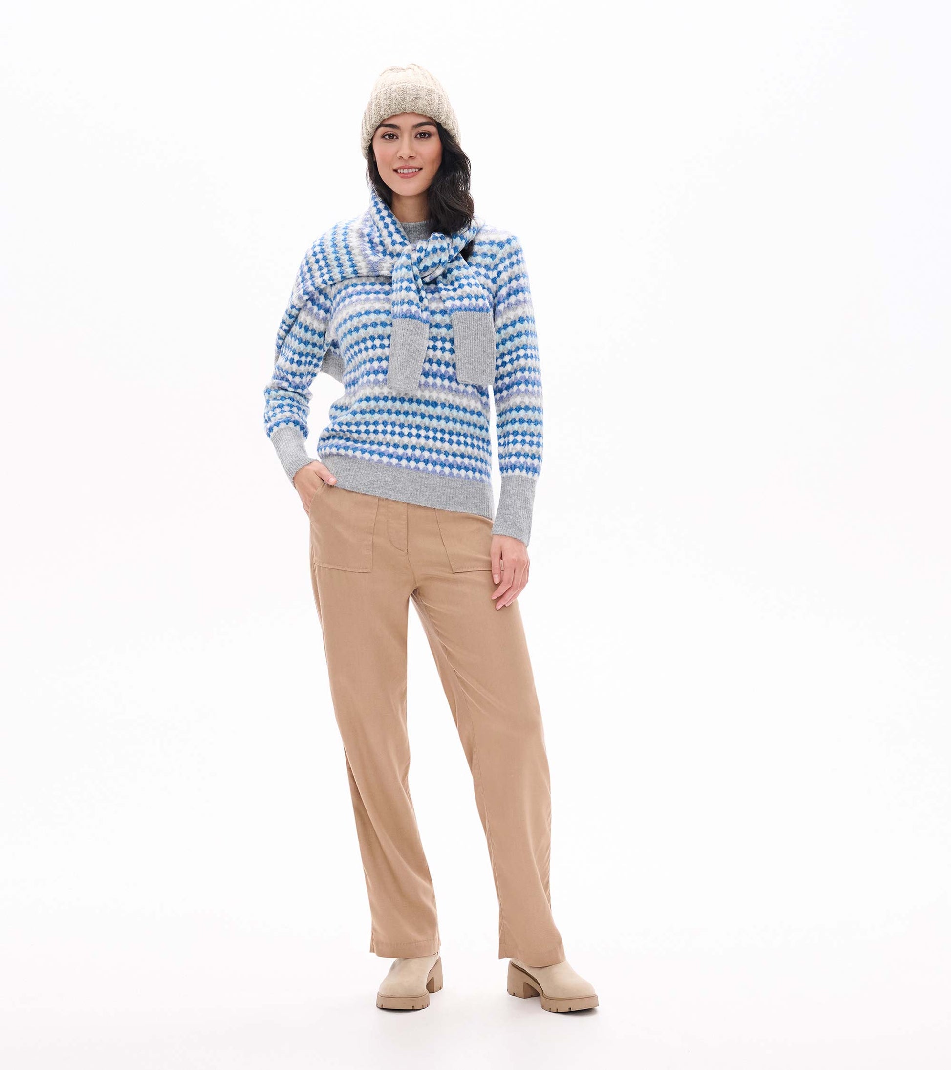 Model wearing blue ombre patterned sweater with gray trim and matching scarf tied at the neck
