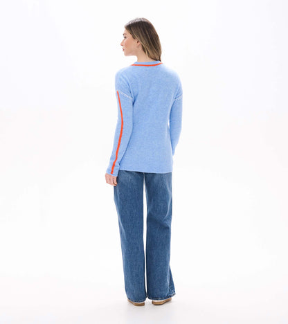 Back view of azure blue Maeve sweater with orange neck trim, orange sleeve stripes, and white shoulder stitching