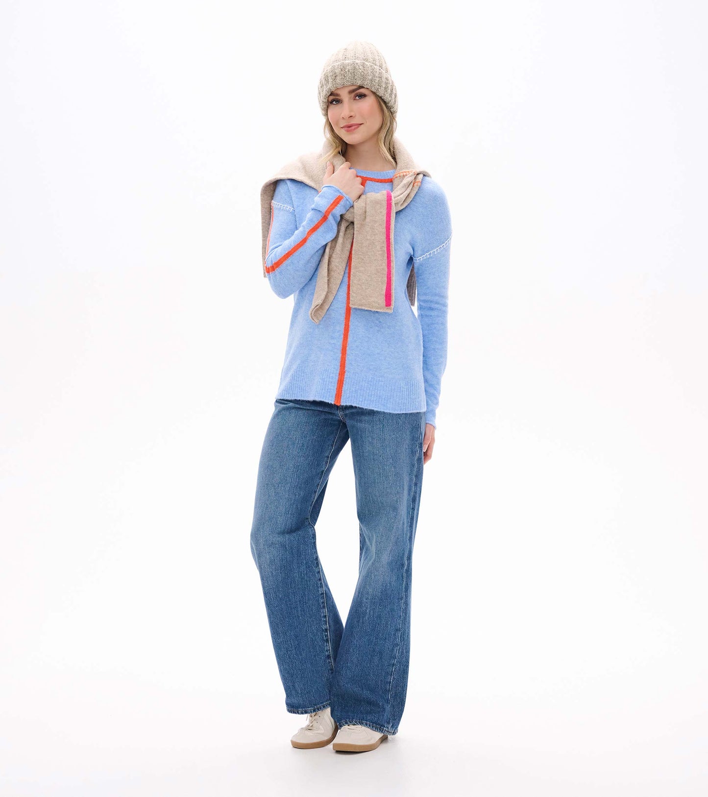 Front view of Maeve sweater in azure blue with orange trim and seam details, styled with jeans and a scarf