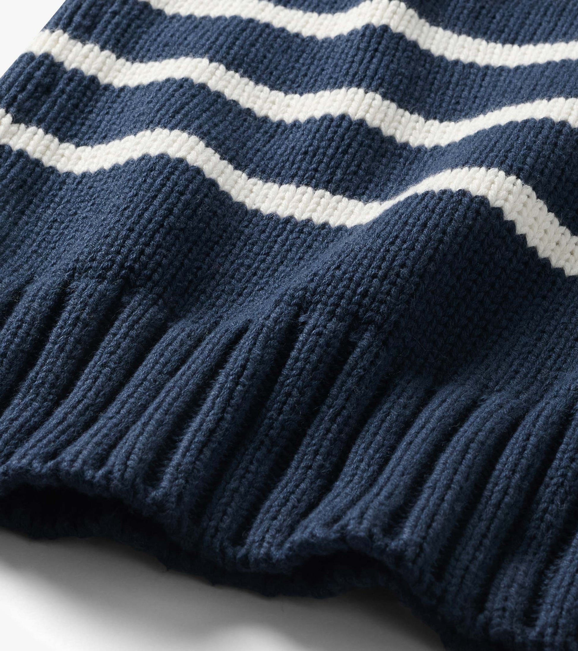 Close-up of navy sweater with cream stripes and wide ribbed hem