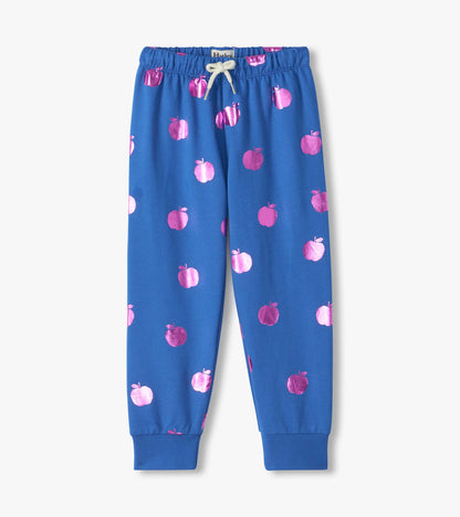 Front view of blue cuffed track pants with metallic pink apple print and white drawstring waist