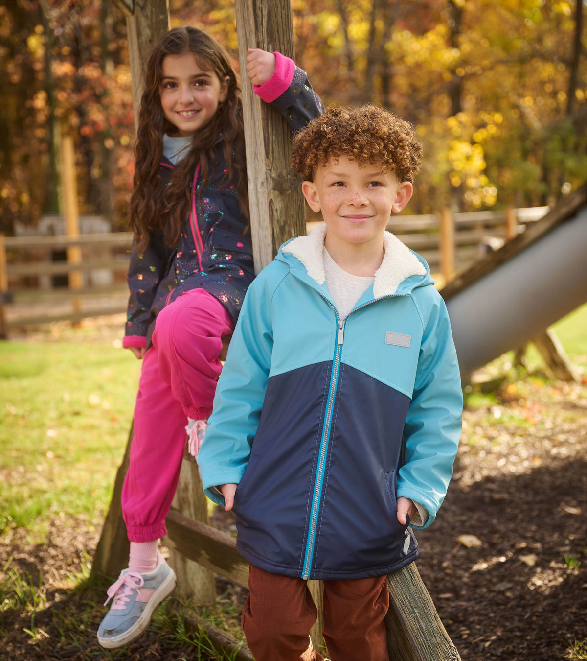 Boy wearing a light blue and navy colourblock sherpa-lined rain jacket at a playground