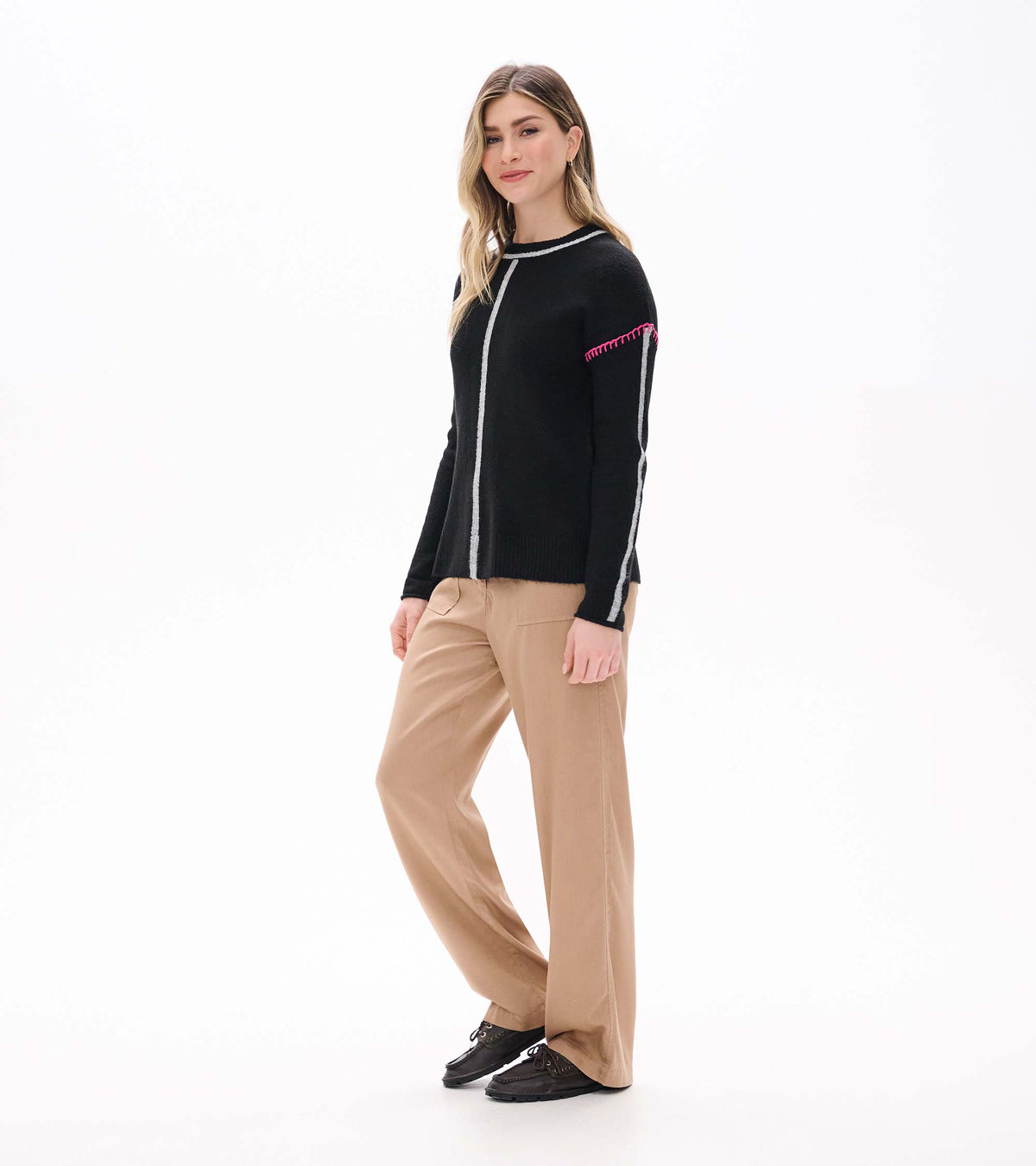 Maeve black sweater on model in angled front view with grey stripes and pink shoulder stitching