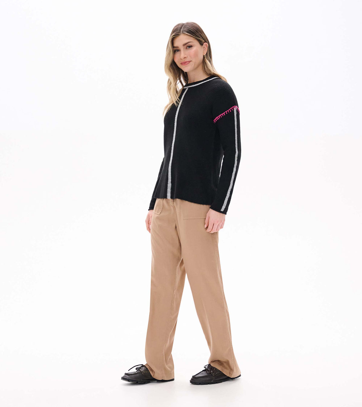 Maeve black sweater on model in side front view with grey sleeve stripe and pink shoulder stitching