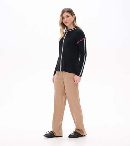 Maeve black sweater on model in side front view with grey sleeve stripe and pink shoulder stitching