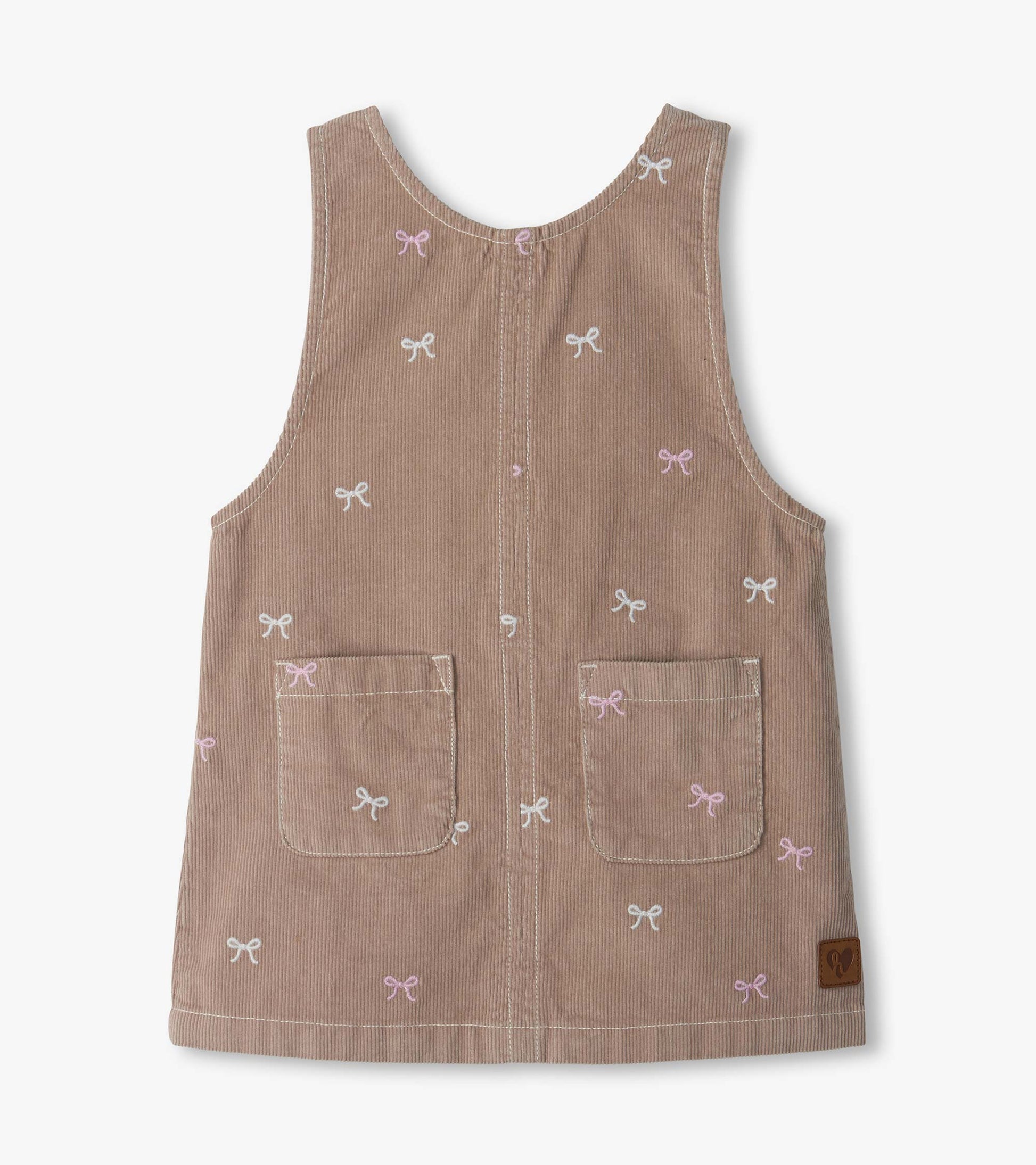 Front view of a dusty pink pinafore dress with bow embroidery and two front patch pockets