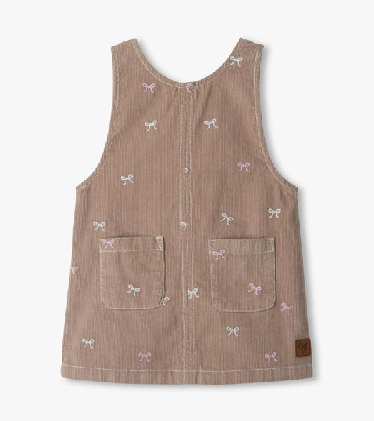 Front view of a dusty pink pinafore dress with bow embroidery and two front patch pockets