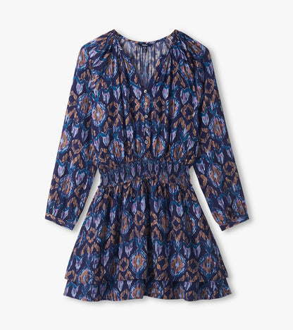 Close-up of mini dress with buttoned V-neck, long sleeves, smocked waist and blue, purple and tan ikat print