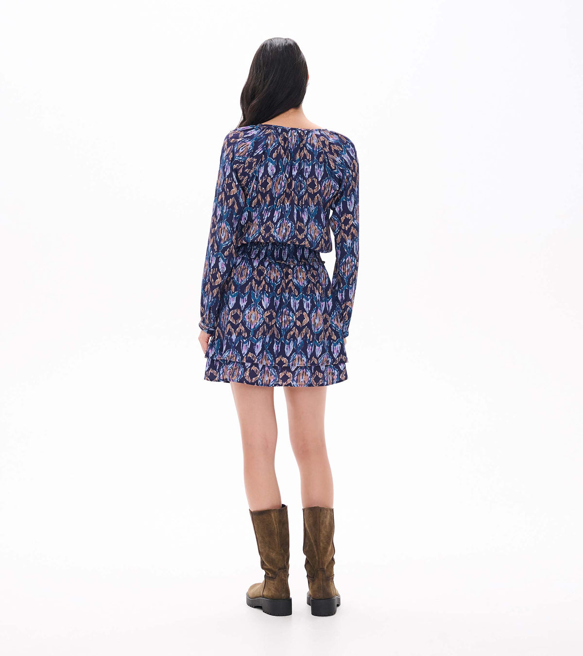 Back view of patterned mini dress with long sleeves, smocked waist, and tiered skirt