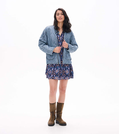 Front view of textured ikat mini dress styled with a light blue quilted jacket and brown boots