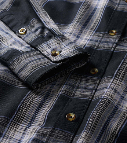 Close-up of black and tan plaid shirt dress showing button placket, collar, and rolled sleeve tab detail