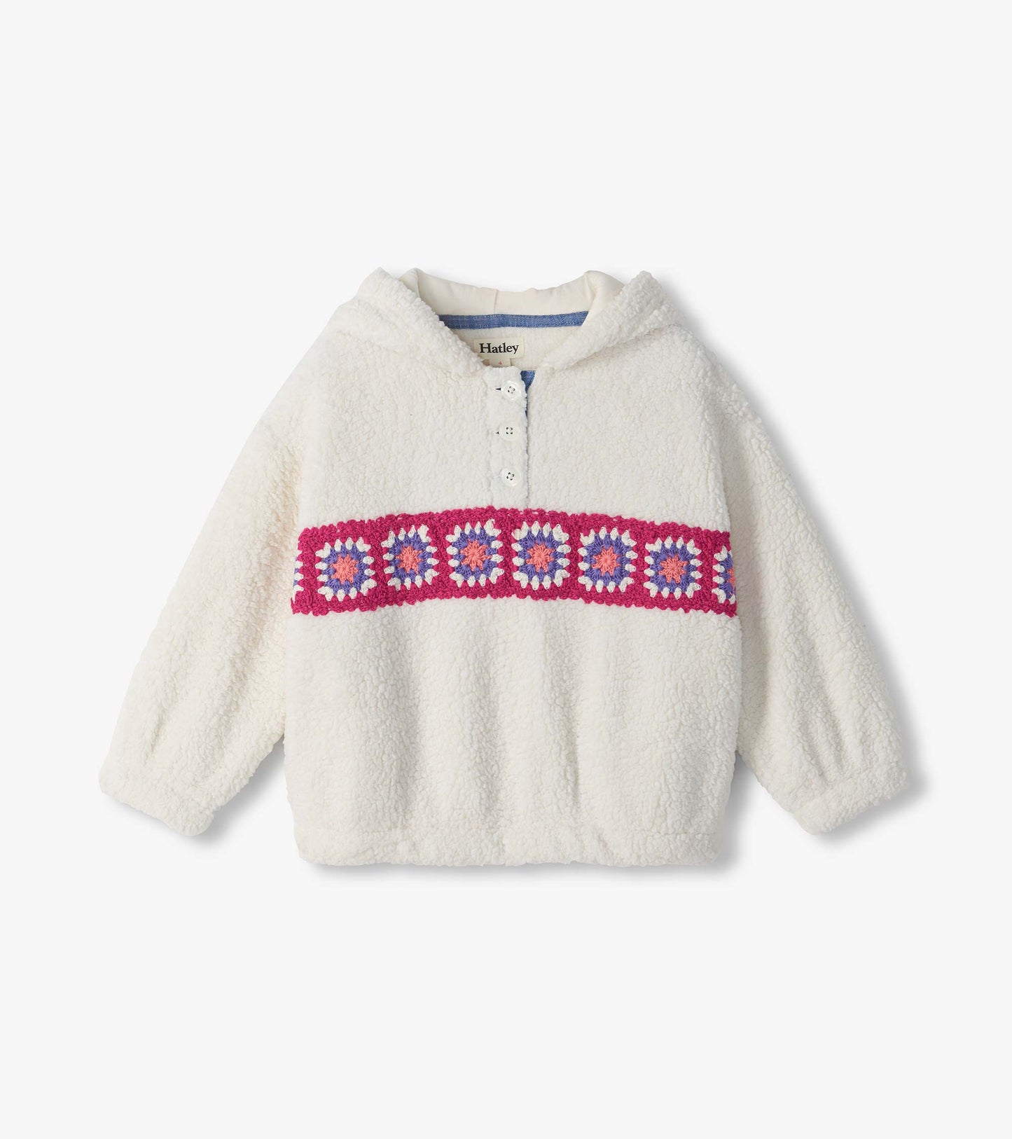 Cream fuzzy pullover with a short button placket and pink, purple, and white crochet band across the chest