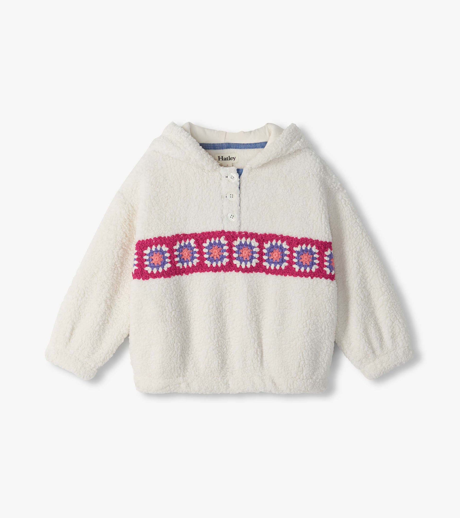 Cream fuzzy pullover with a short button placket and pink, purple, and white crochet band across the chest
