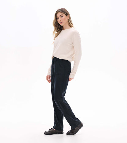 Women's black wide leg pants shown in side view with a cream sweater and black loafers