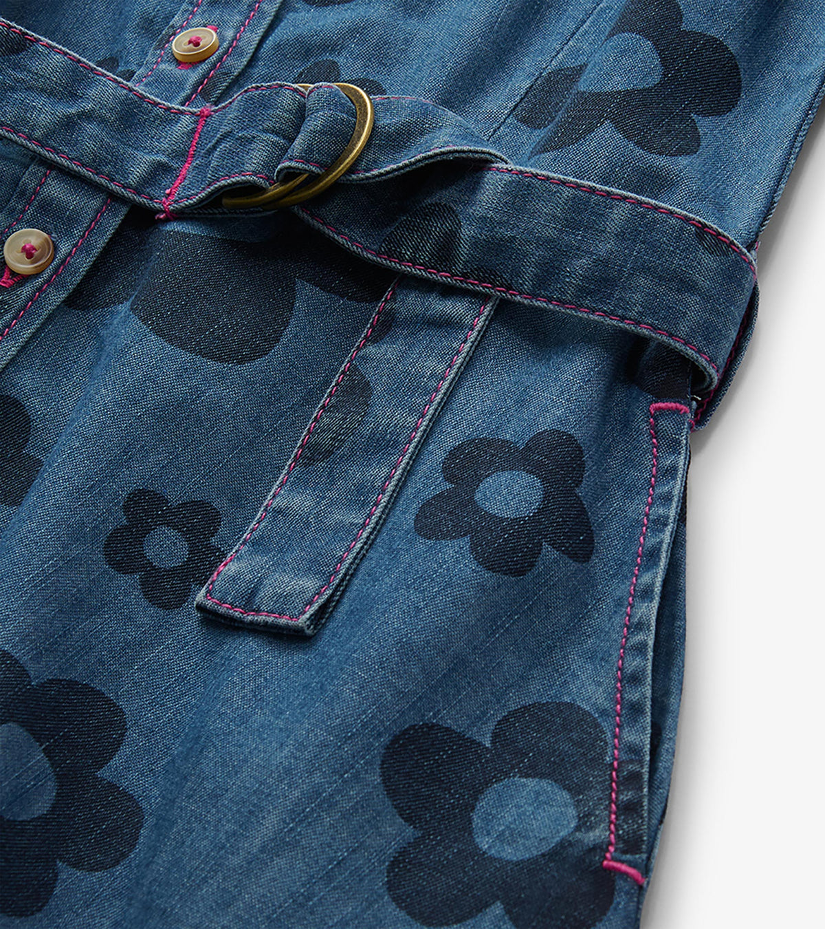 Close-up of blue jean dress with large flower print, pink stitching, button front, and ring-belt tie
