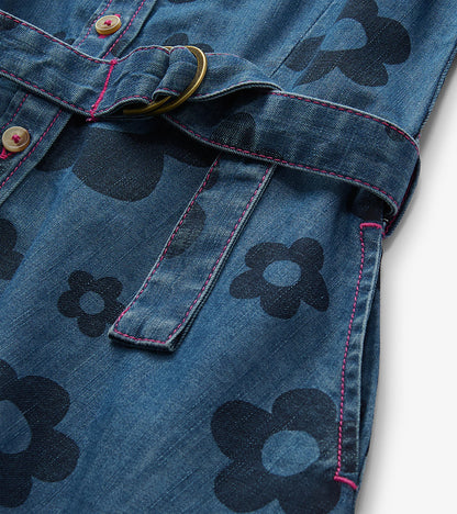 Close-up of blue jean dress with large flower print, pink stitching, button front, and ring-belt tie