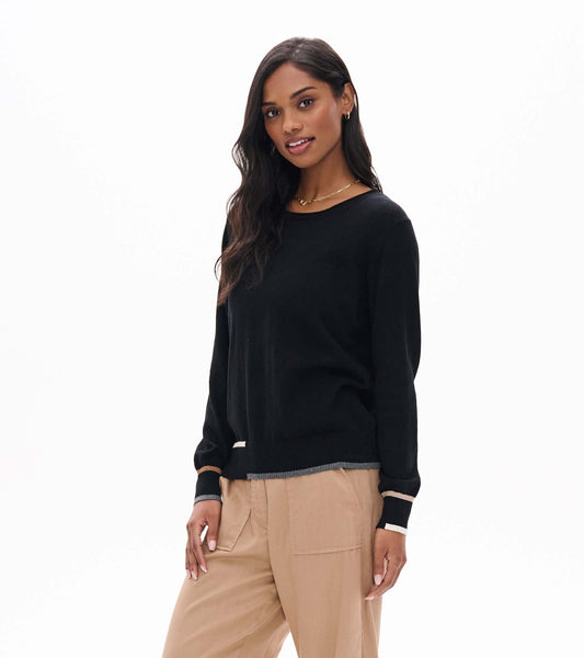 Model wearing black crew neck sweater with contrast trim at cuffs and hem, angled front view