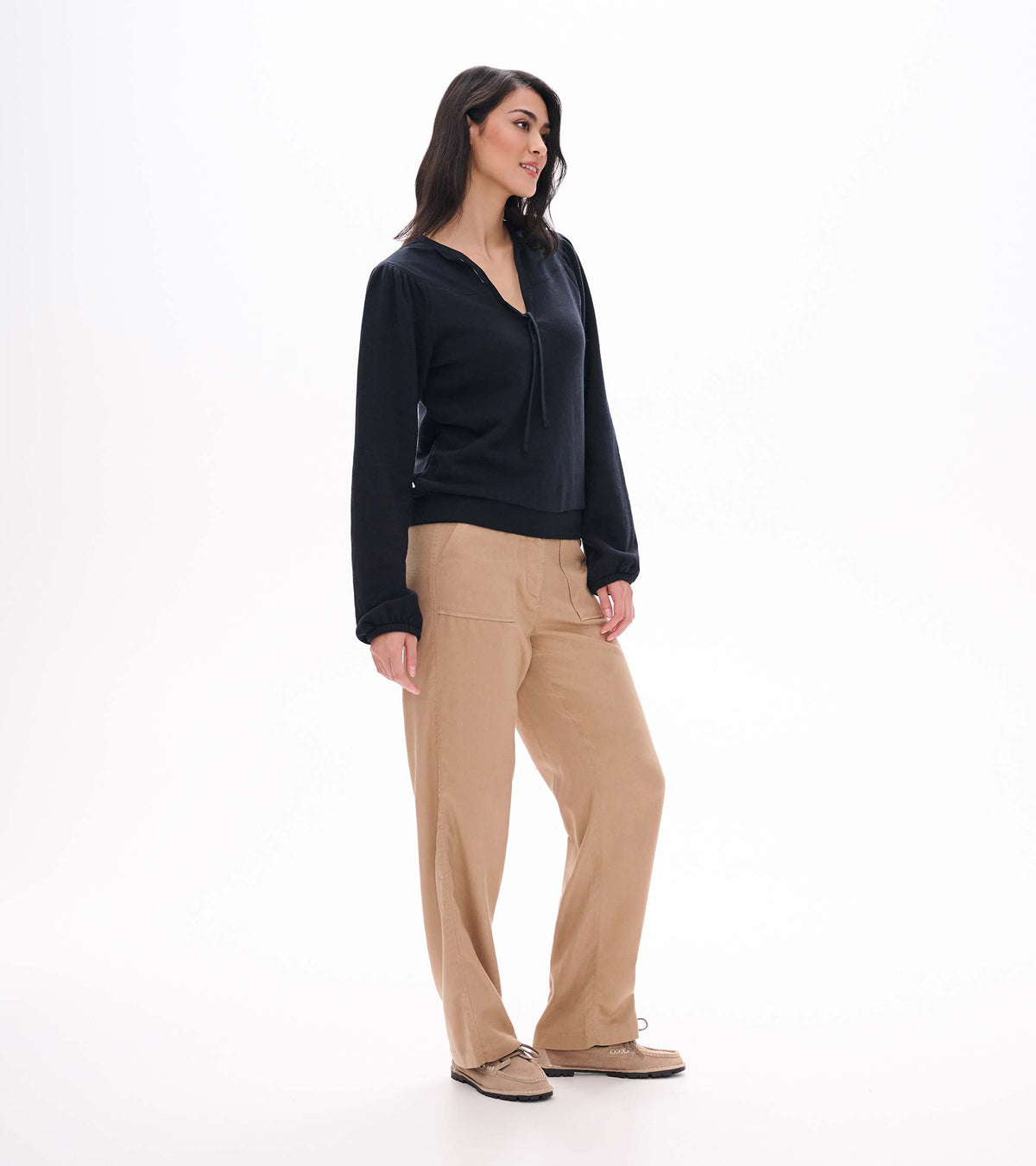 Side view of black long sleeve top with tie neckline, puffed shoulders, and banded hem on model