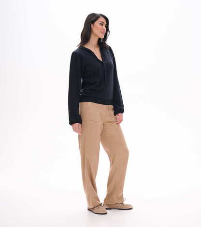 Side view of black long sleeve top with tie neckline, puffed shoulders, and banded hem on model