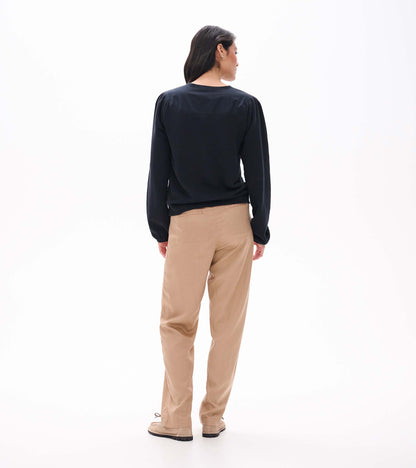 Back view of black long sleeve top with gathered shoulder seams and banded hem on model