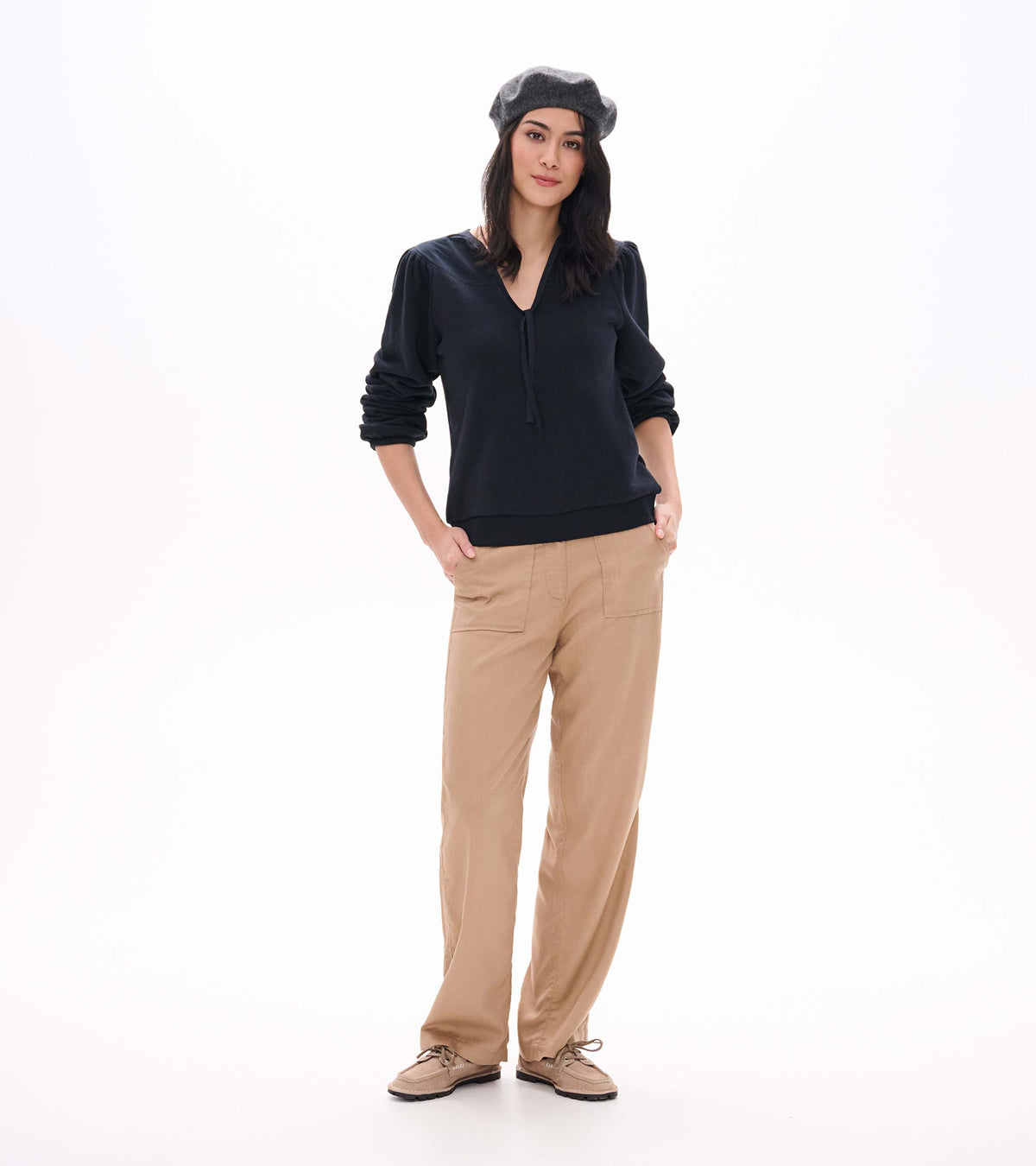 Black long sleeve top with tie neckline and puffed shoulders, shown on model with sleeves pushed up