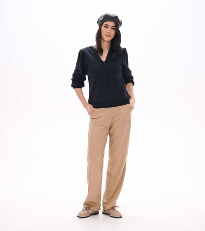 Black long sleeve top with tie neckline and puffed shoulders, shown on model with sleeves pushed up