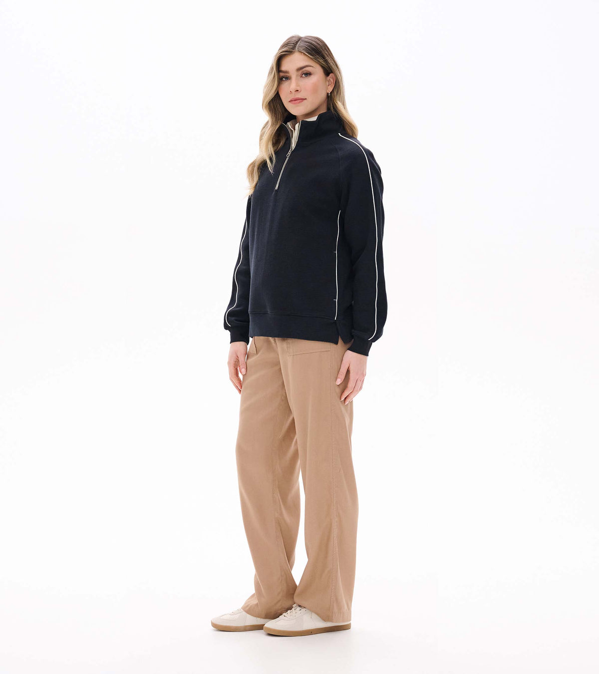 Black 1/4 zip knit top shown on model from front left angle with white sleeve piping