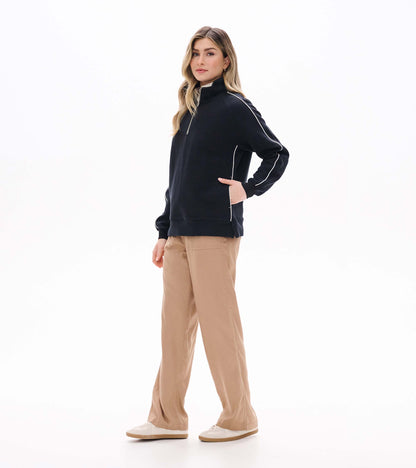 Black 1/4 zip knit top on model from side angle with stand collar and white piping detail