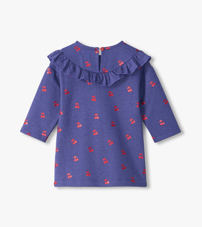 Back view of purple infant dress with red cherry print, long sleeves, ruffle yoke, and button closure