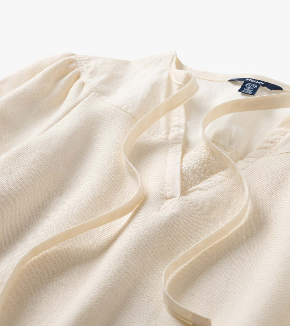Close-up of cream top neckline with tie detail, gathered shoulders, and contrasting yoke trim