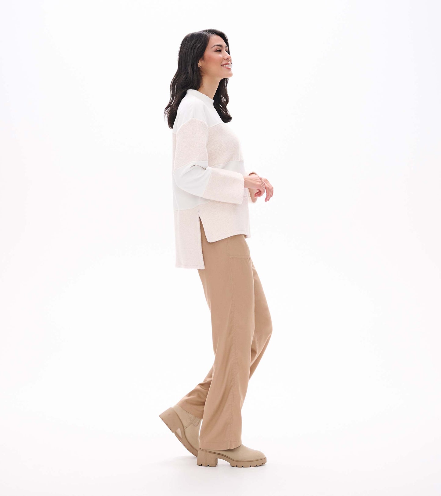 Side view of oatmeal long sleeve top with textured horizontal stripe panels and side slit hem