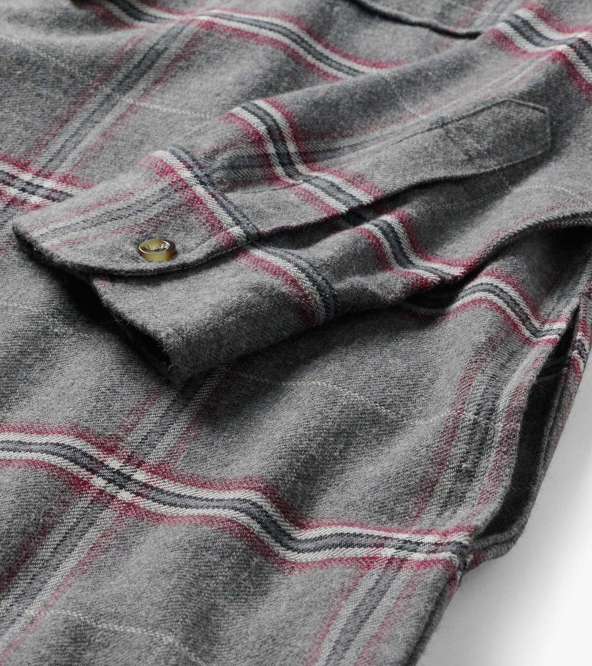 Close-up of gray plaid dress fabric with chest flap pocket and button detail
