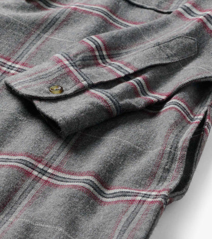 Close-up of gray plaid dress fabric with chest flap pocket and button detail