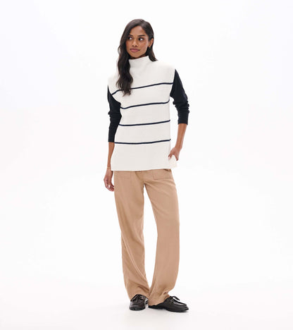 Cream sleeveless striped sweater tunic layered over a black long sleeve top, front view