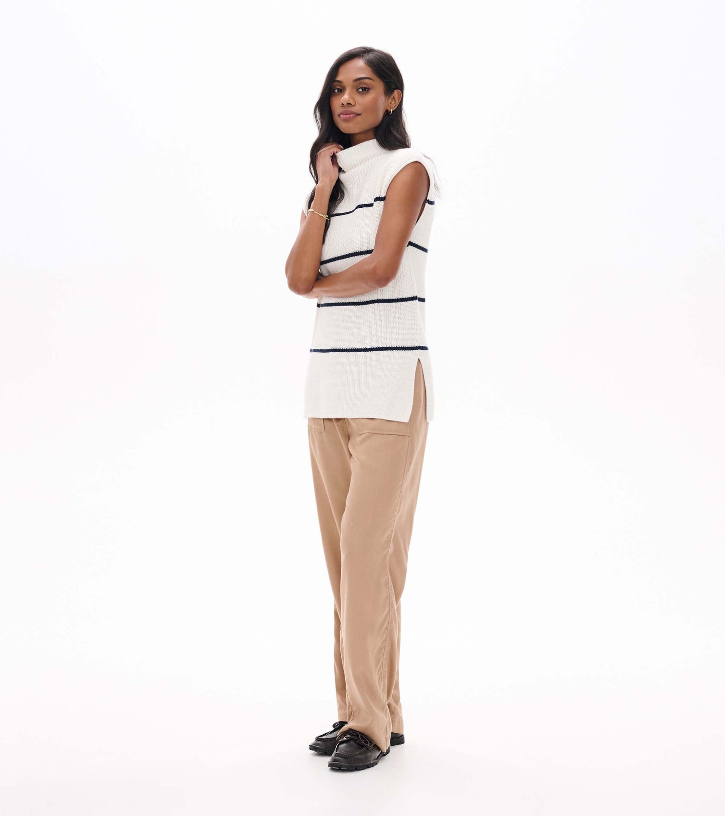 Side view of cream sleeveless sweater tunic with navy stripes, mock neck, and side slit hem