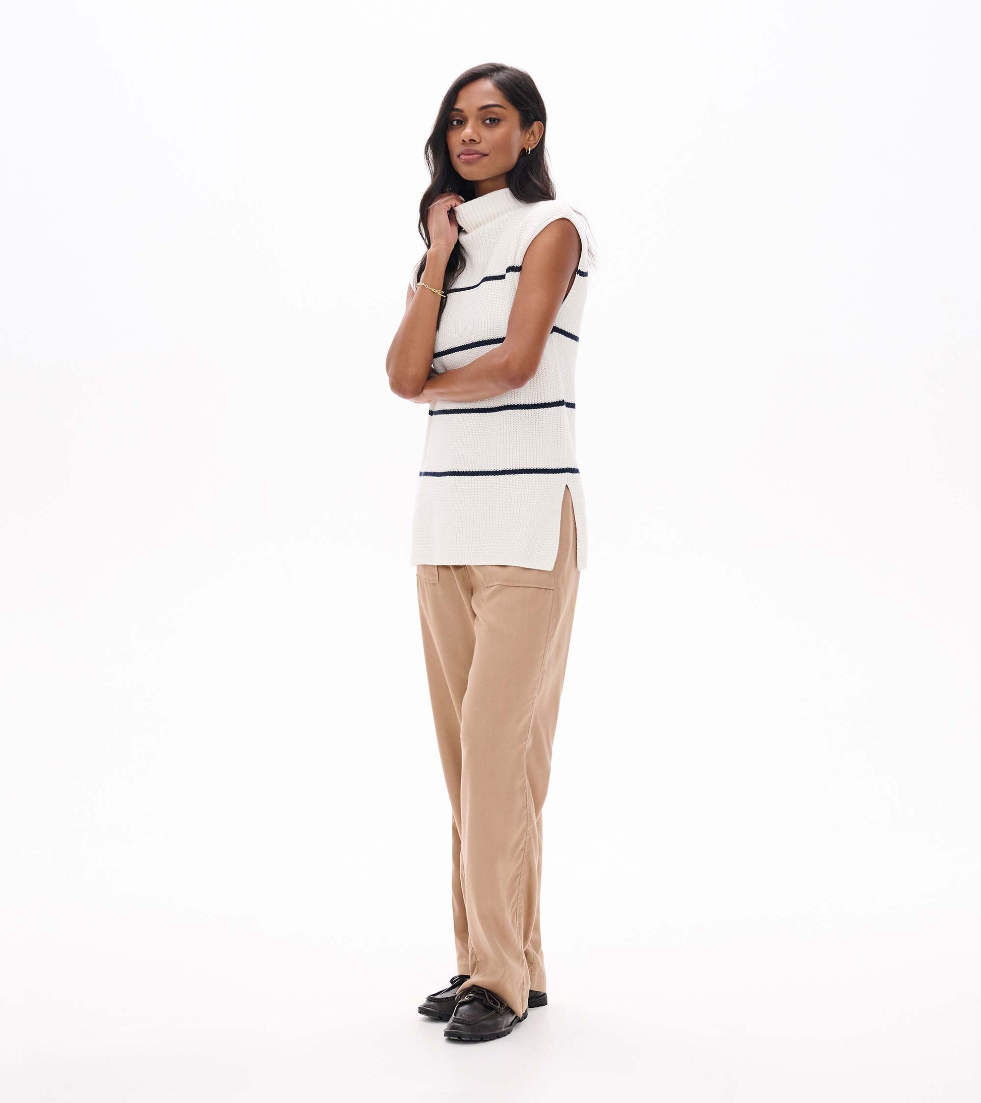 Side view of cream sleeveless sweater tunic with navy stripes, mock neck, and side slit hem