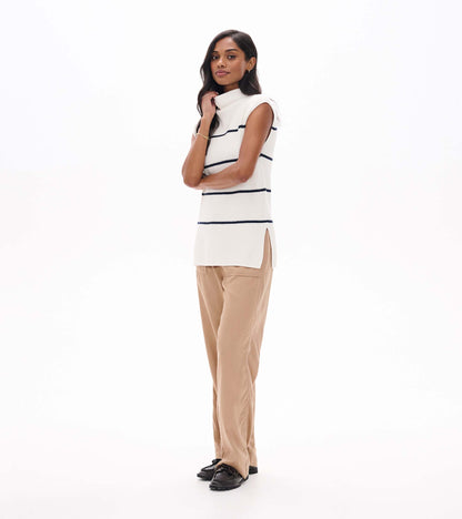 Side view of cream sleeveless sweater tunic with navy stripes, mock neck, and side slit hem