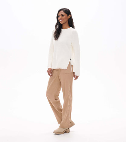 Cream raglan sweater on model in angled front view, showing side zip opening and split hem