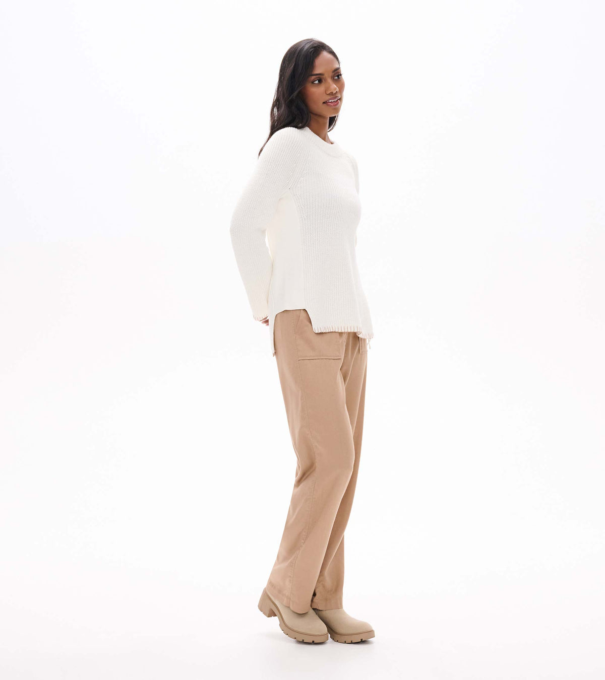 Side view of cream raglan sweater on model, showing side zip opening and split hem